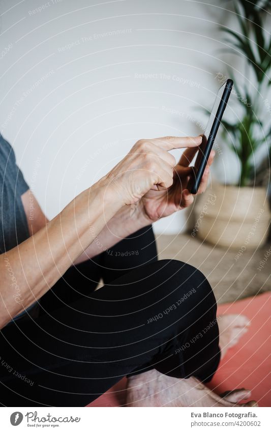 mature caucasian senior woman practicing yoga pose at home. using mobile phone. Technology and Healthy lifestyle technology internet online wireless indoors