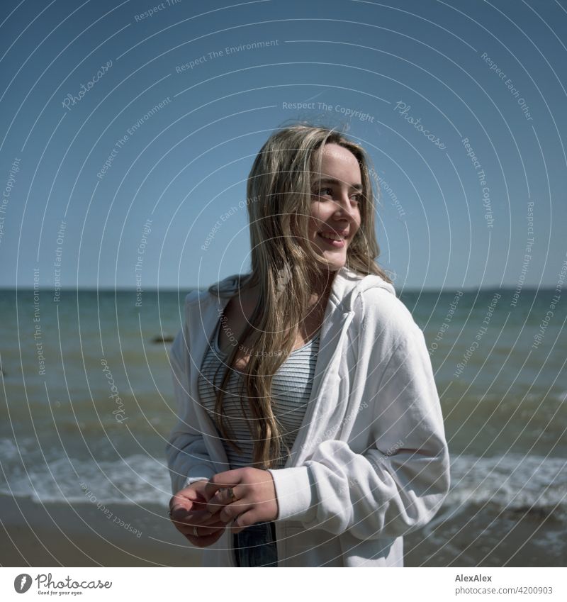 Analogue rectangular image of a beautiful blonde girl standing on the beach of the Baltic Sea and looking to the side Girl Smiling joyfully Landscape by Blonde