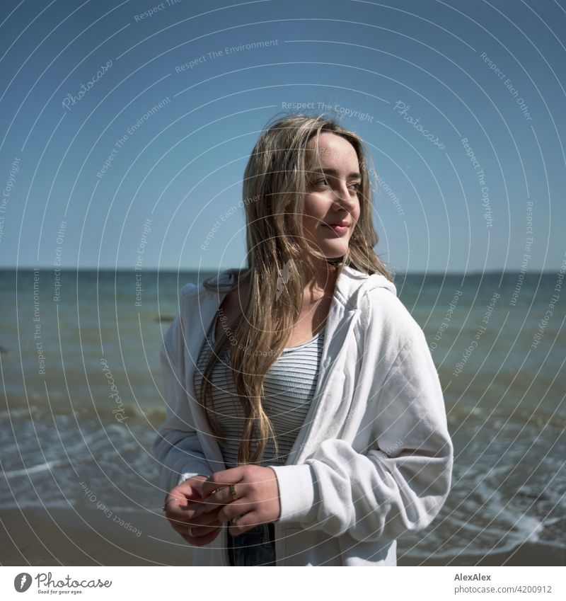 Analogue rectangular image of a beautiful blonde girl standing on the beach of the Baltic Sea and looking to the side Girl Smiling joyfully Landscape by Blonde