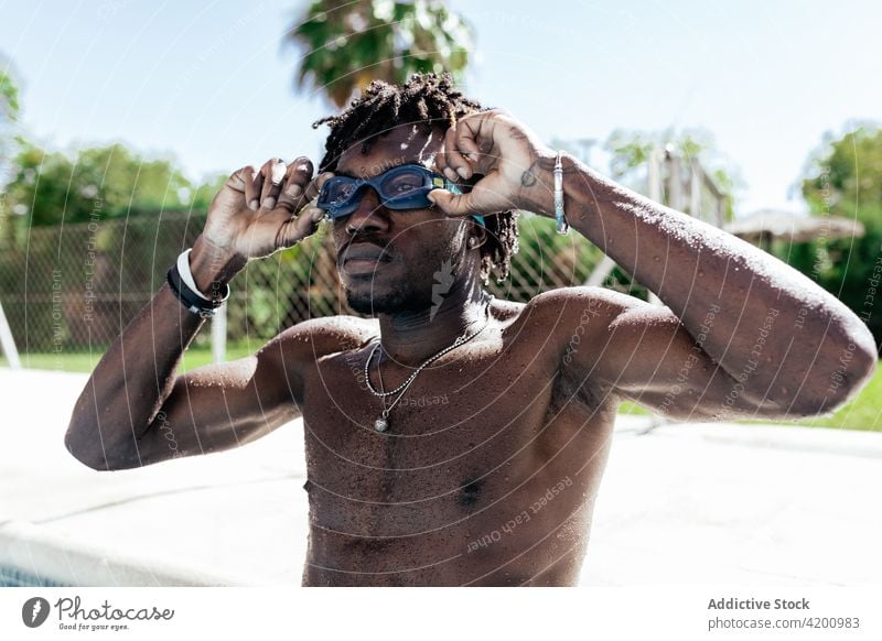 Muscular black guy adjusting swimming goggles after training in outdoor pool man swimmer shirtless muscular athlete poolside confident wellness sportsman