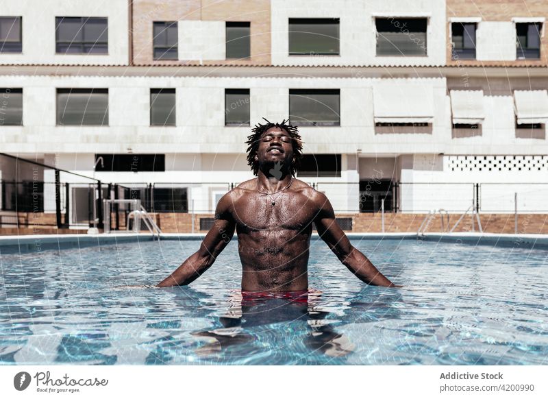 Black man in swimming pool summer vacation enjoy water naked torso carefree sunny shorts male ethnic black african american holiday recreation eyes closed