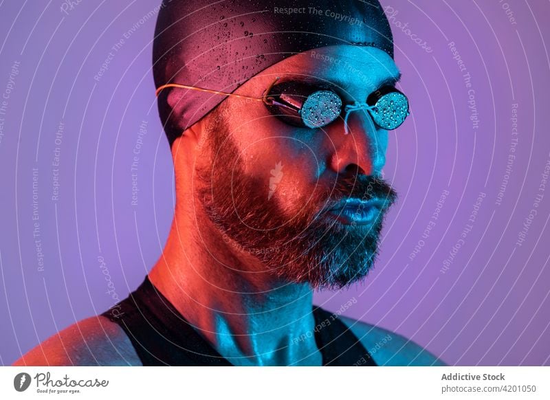 Side view studio portrait of a swimmer with cap and goggles man background glasses bearded healthy face young isolated white people one athlete lifestyle sport