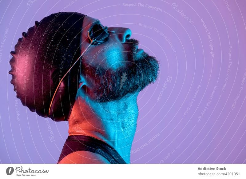 Portrait of a swimmer with cap and goggles looking up studio man portrait background glasses bearded healthy face young isolated white people one athlete