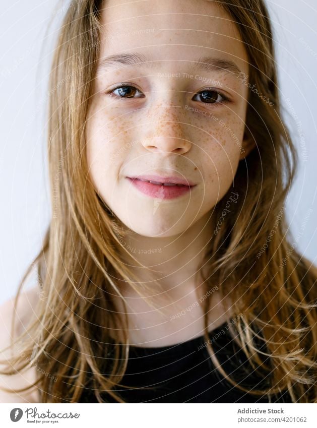 Happy girl with long hair and freckles against white background child laugh portrait fun joy humor delight positive toothy smile optimist human face studio shot