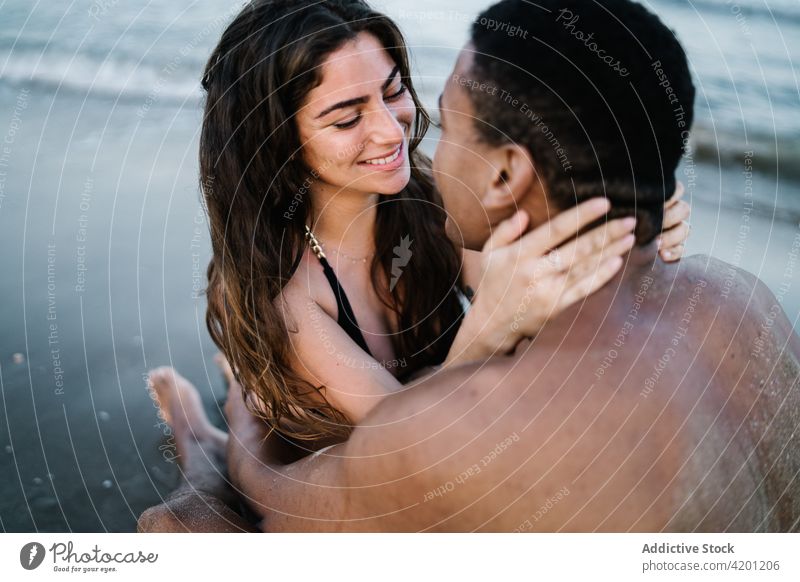 Smiling multiethnic couple of travelers embracing on sea shore embrace love relationship honeymoon romance pleasure seashore vacation rest multi-ethnic tourism