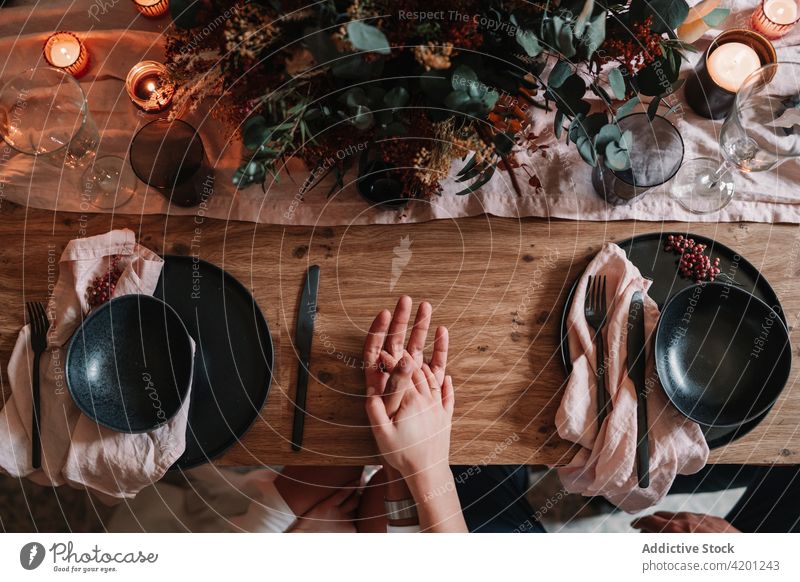 Faceless newlywed couple holding hands at table on wedding day decor vintage celebrate marriage love restaurant relationship served plate bowl cutlery flower