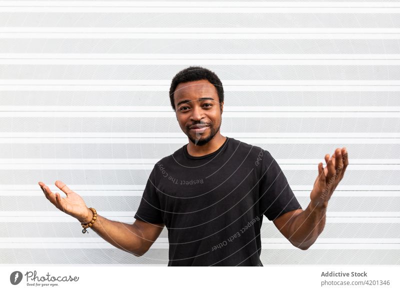 Cheerful black male standing near striped wall man cheerful sincere friendship happy portrait content glad smile candid positive friendly toothy smile enjoy