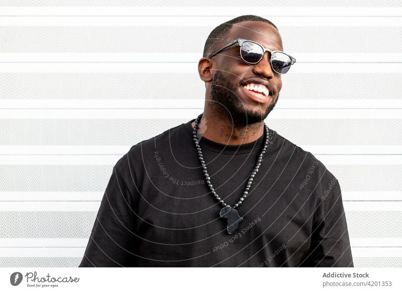 Cheerful black male standing near striped wall man cheerful sincere friendship happy portrait racism content glad smile candid positive friendly toothy smile