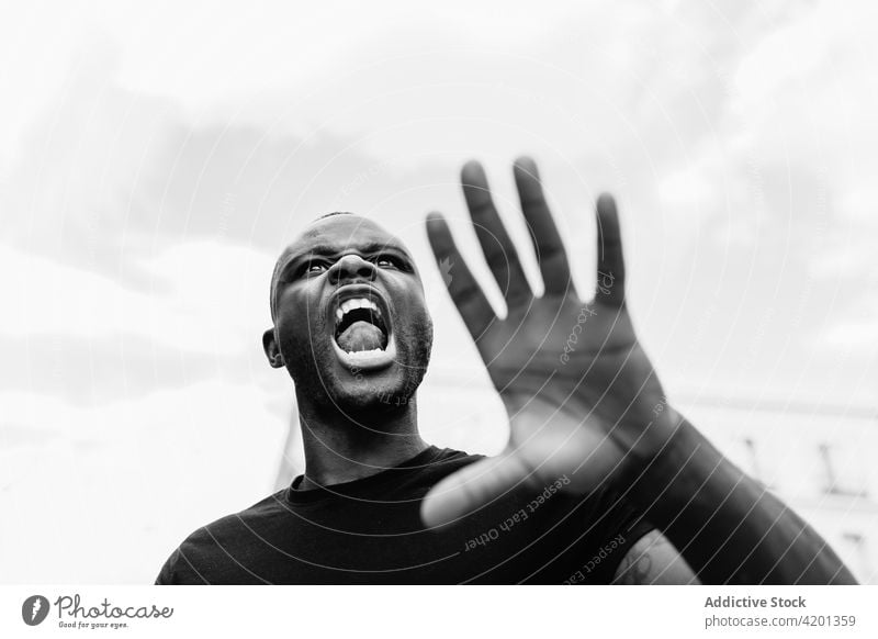 Aggressive black protester shouting on city street stop aggressive angry blm rebel man town portrait restriction show gesture annoyed reject ethnic scream