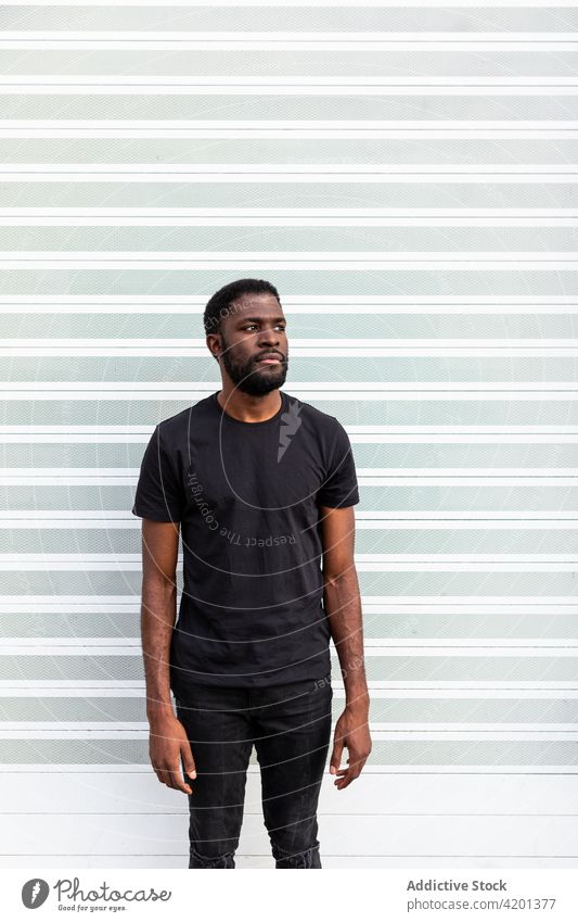 Cheerful black male standing near striped wall man cheerful sincere friendship happy portrait content glad smile candid positive friendly toothy smile enjoy