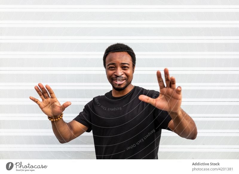 Cheerful black male standing near striped wall man cheerful sincere friendship happy portrait content glad smile candid positive friendly toothy smile enjoy