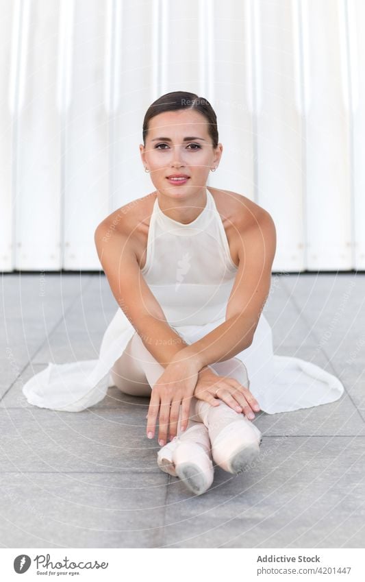 Graceful ballerina with crossed legs on pavement art ballet legs crossed grace feminine allure gentle portrait woman white dress pointe shoe professional tender