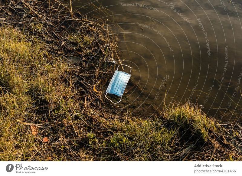 Used medical mask in water of lake pollute environment garbage used concept dirty rubbish waste protect pond debris nature ecology earth save risk damage hazard