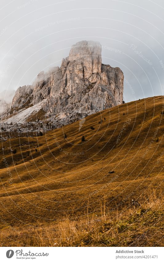 Rocky mountain and grassy hills rock landscape range nature highland slope cloud peak italy dolomites steep scenery picturesque rough yellow ridge environment