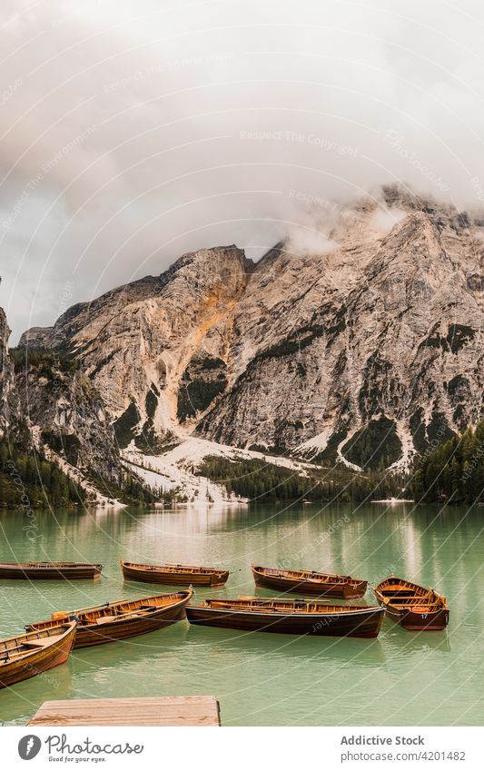 Rocky mountain and lake landscape near wood boats rock range nature peak fog rough highland majestic dolomites italy water travel tourism ridge picturesque