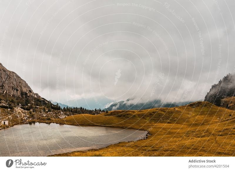 Small lake in foggy highlands mountain hill rock landscape range nature rough dolomites italy water travel tourism ridge picturesque scenic scenery shore