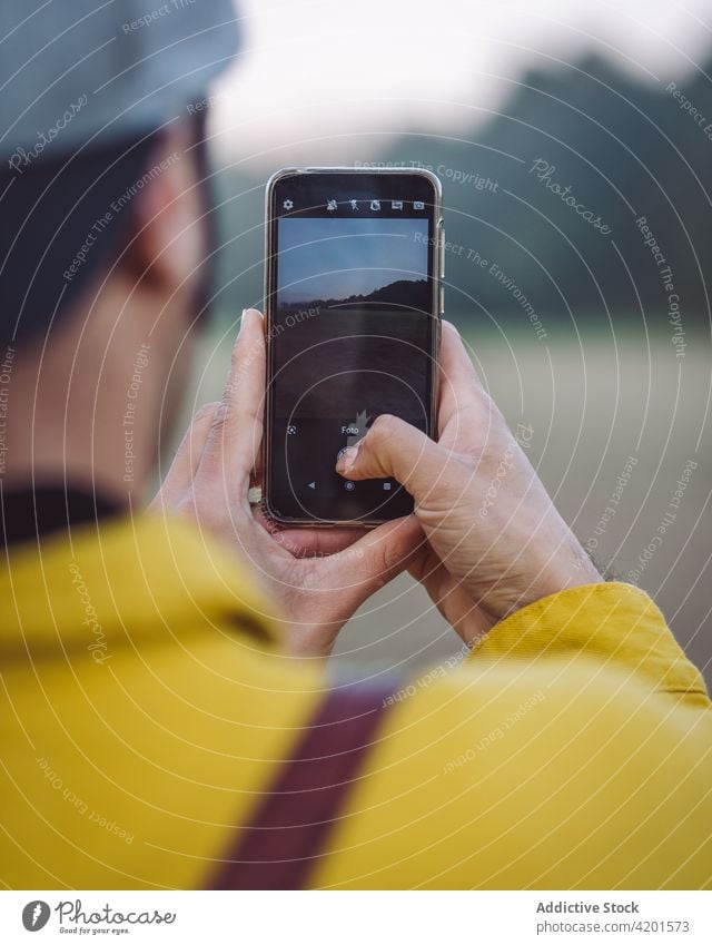 Man taking photo in foggy countryside man smartphone backpacker nature hike photography meadow denim lifestyle device gadget young mobile beard capture