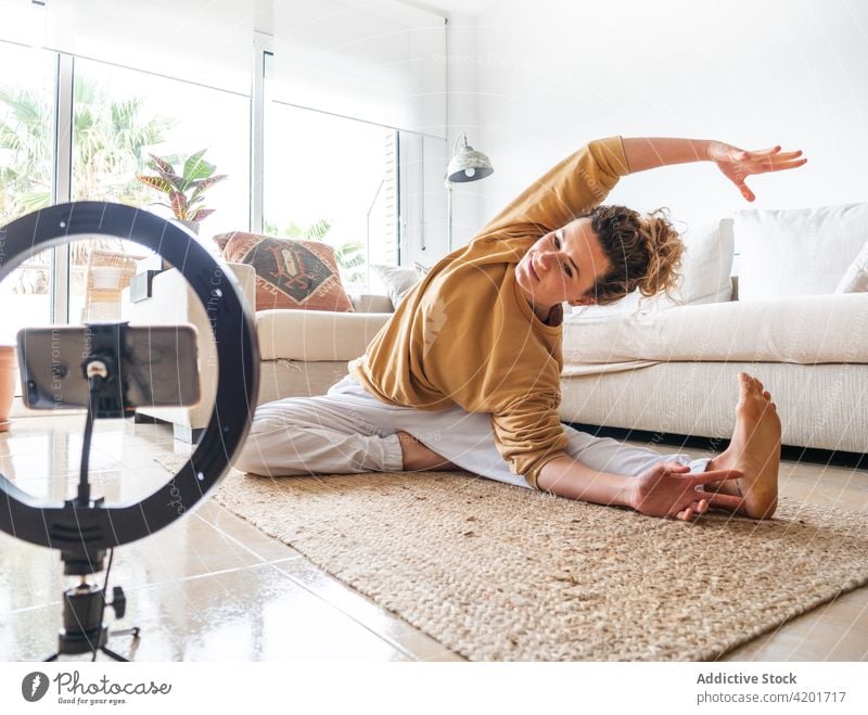 Fit woman sitting on floor in revolved head to knee pose stretch yoga living room parivrtta janu sirsasana mindfulness flexible zen practice serene barefoot