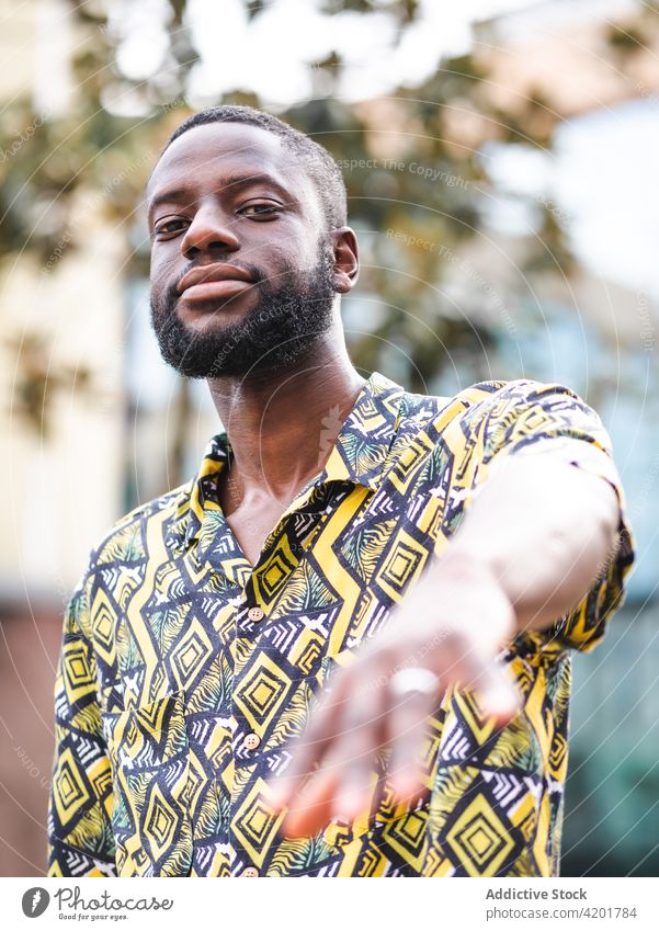 Black man standing on the street looking at camera friendly masculine macho ornament portrait city black african american ethnic shirt apparel unshaven enjoy