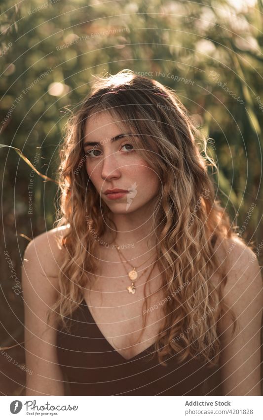 Long haired woman in swimsuit standing in green garden long hair sunlight portrait beauty feminine nature summer young charming female brunette wavy hair calm