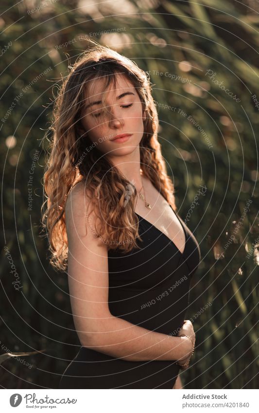 Long haired woman in swimsuit standing in green garden long hair sunlight portrait beauty feminine nature summer eyes closed young charming female brunette