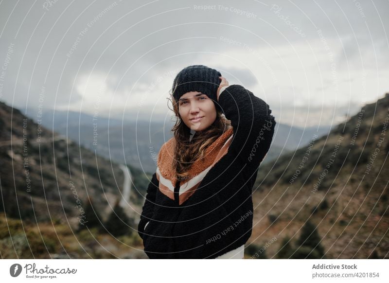 Cheerful woman putting on hat on picturesque highlands put on cloudy gloomy rough cheerful smile nature weather happy young beautiful joy cadiz spain glad