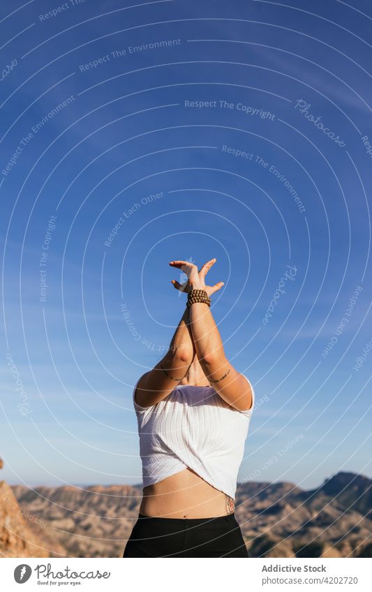 Young woman standing in yoga pose on mountain posture practice healthy highland energy balance female upward hand posture nature cliff freedom exercise stretch