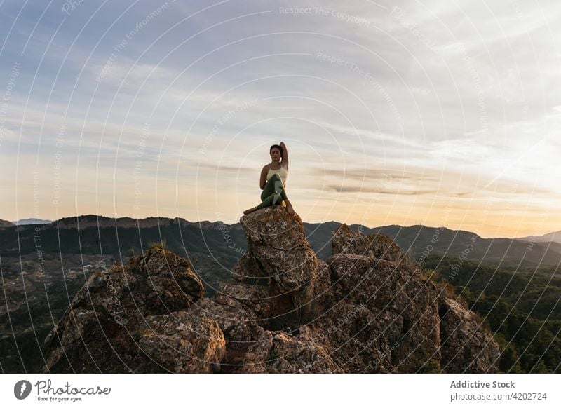 Young female in cow face pose on hilltop woman yoga sunset cliff vitality zen practice harmony gomukhasana eyes closed flexible energy twilight evening balance