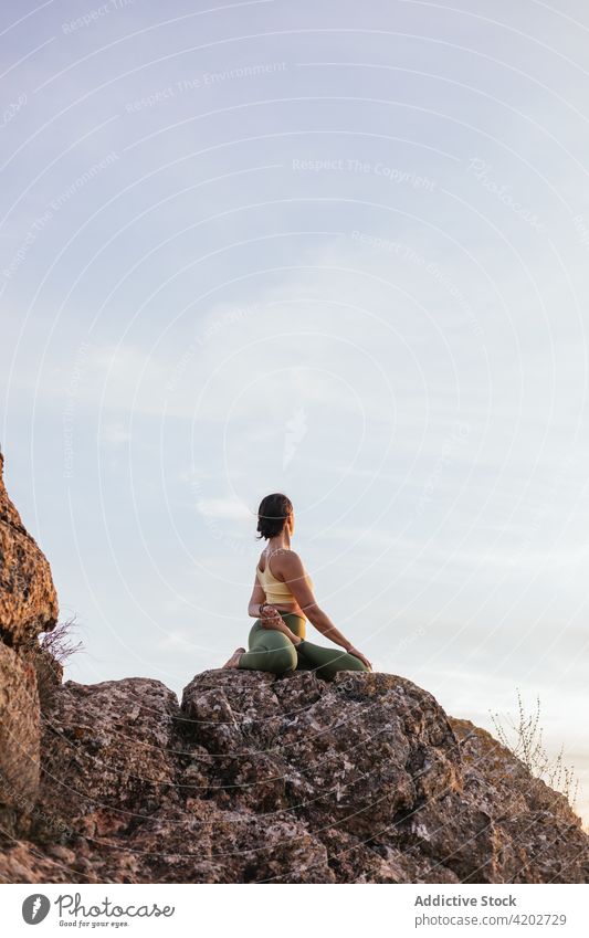 Young female doing yoga on hilltop woman sunset cliff padmasana vitality zen practice harmony flexible energy twilight evening balance tranquil healthy position