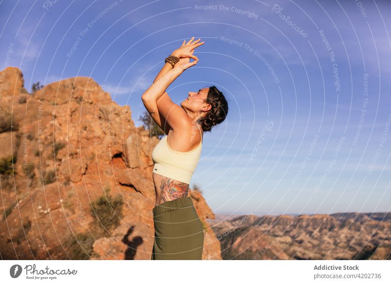 Young woman standing in yoga pose on mountain posture practice healthy highland energy balance female upward hand posture nature cliff freedom exercise stretch