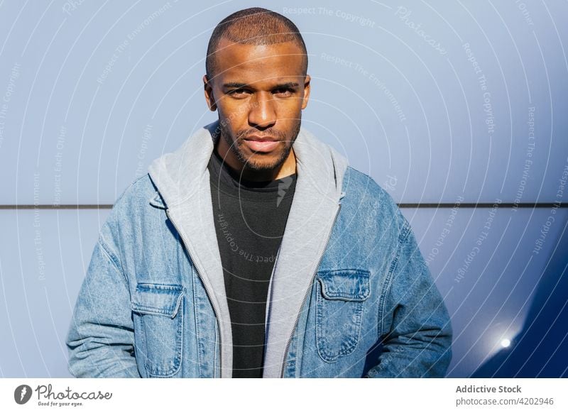 Masculine black man in hoodie near tiled wall hand in pocket style casual masculine cool macho brutal portrait town city modern street contemplate emotionless