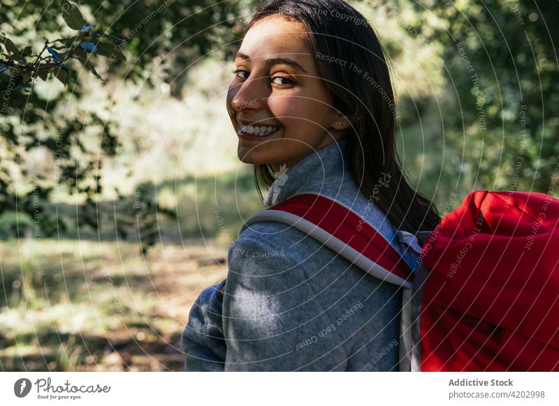 Cheerful woman with backpack hiking in forest hiker happy sunlight active cheerful nature smile young female lifestyle activity recreation wellness healthy