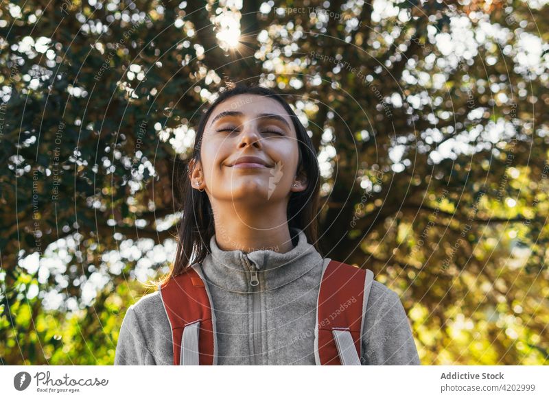 Cheerful woman with backpack hiking in forest hiker happy sunlight active cheerful nature smile young female lifestyle activity recreation wellness healthy