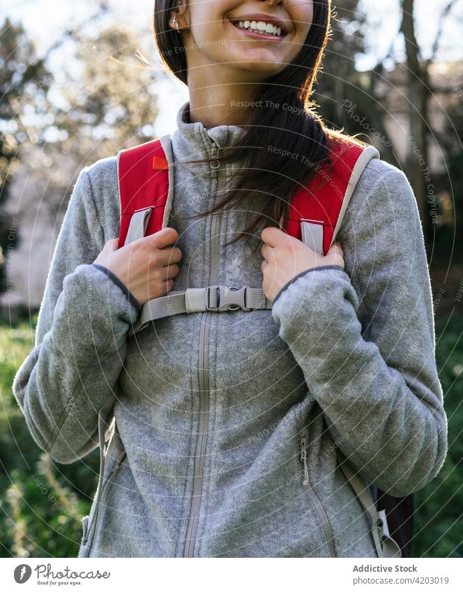 Anonymous woman with backpack hiking in forest hiker happy sunlight active cheerful nature smile young female lifestyle activity recreation wellness healthy