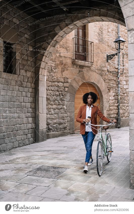 Ethnic woman walking with bicycle along street commute city bike trendy black african american ethnic urban contemporary vehicle town sidewalk pavement