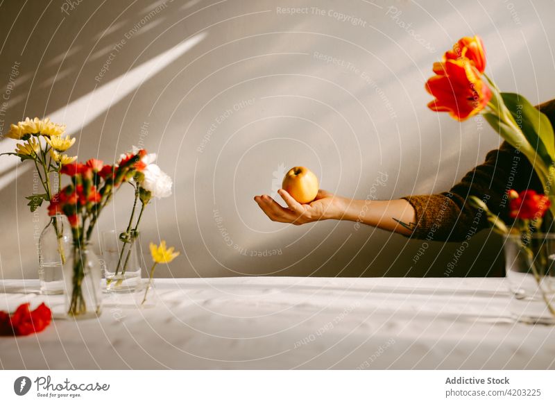 Person throwing apple in studio with flowers person ripe levitate fly fruit tulip carnation bloom toss blossom food bouquet floral delicious natural vitamin