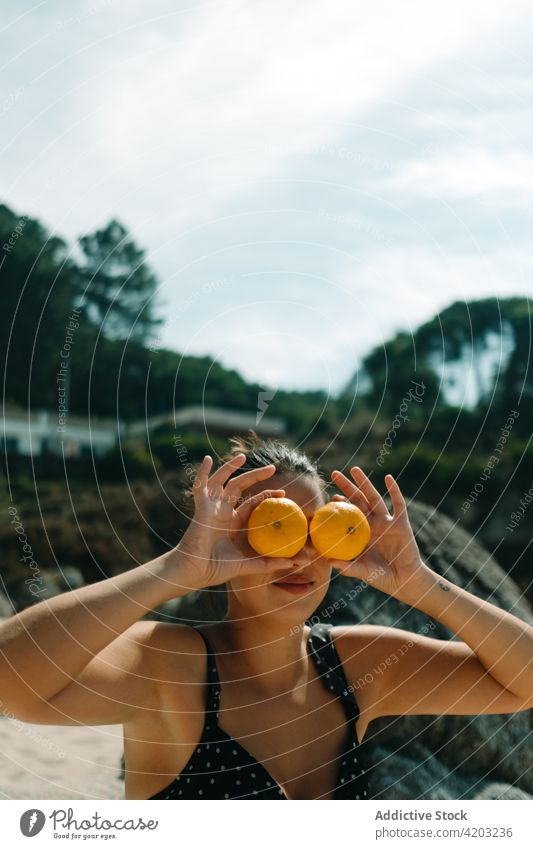 Woman on the beach with bikini covering her eyes with some oranges body woman skin slim female close up white health beauty fitness thin figure swimwear hips