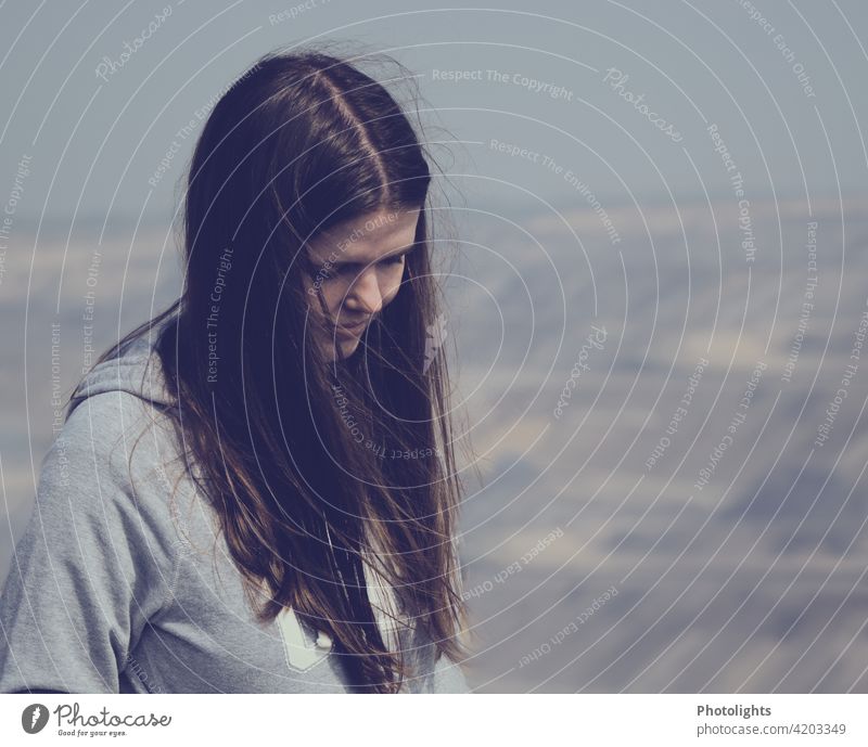 Young woman with long hair and grey top looks at the floor portrait youthful Woman Long Gray Top part Brown Sun sunny Adults pretty Human being Exterior shot