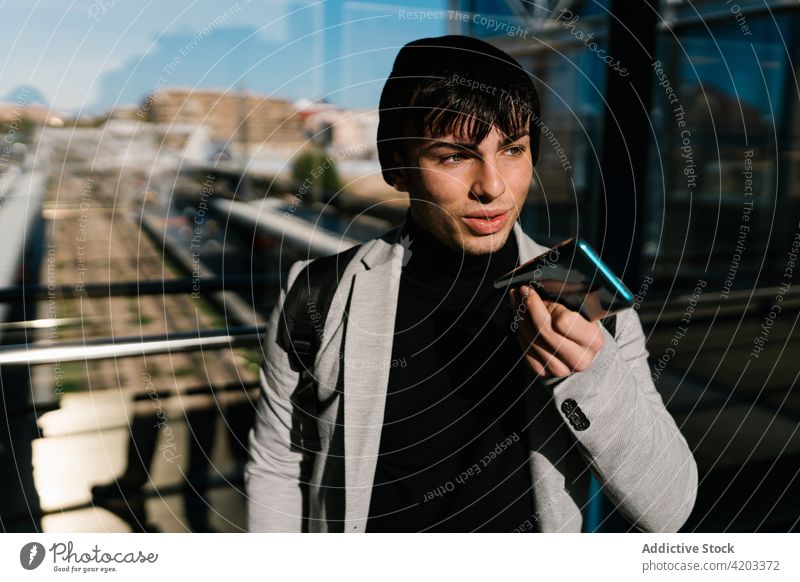 Man recording audio message on smartphone at railway station man voice student travel hallway male backpack using mobile connection communicate talk speak