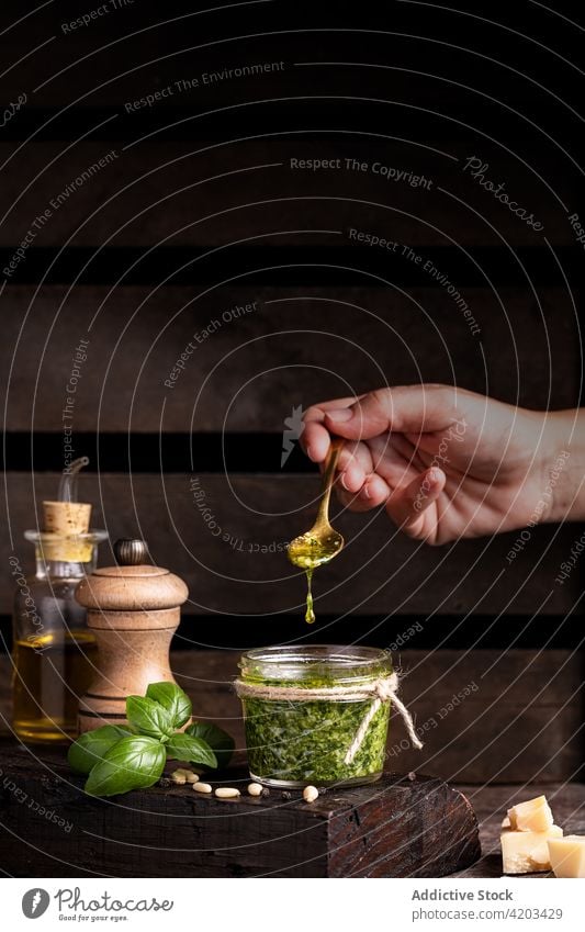 Crop person preparing pesto sauce oil add pour hand ingredient recipe food prepare cheese basil tradition cuisine italian fresh culinary gourmet kitchen pot