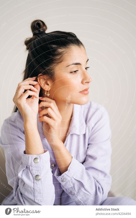 Young woman touching earring on light background feminine charming romantic dreamy enjoy portrait accessory creative design modern style show mindful friendly