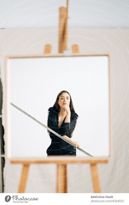 Wistful woman reflecting in mirror on easel reflection wistful art feminine gentle sensitive alone charming earring romantic dreamy accessory modern style