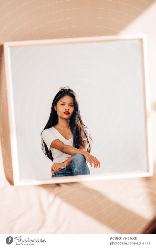 Young confident woman reflecting in mirror reflection thoughtful pensive calm bright red lips serious female young dark hair appearance trendy alone focus