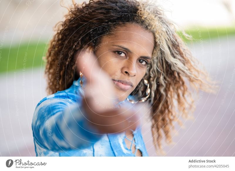 Stylish ethnic woman with dyed curly hair looking at camera hipster confident hand style trendy human face urban informal follow me modern african american