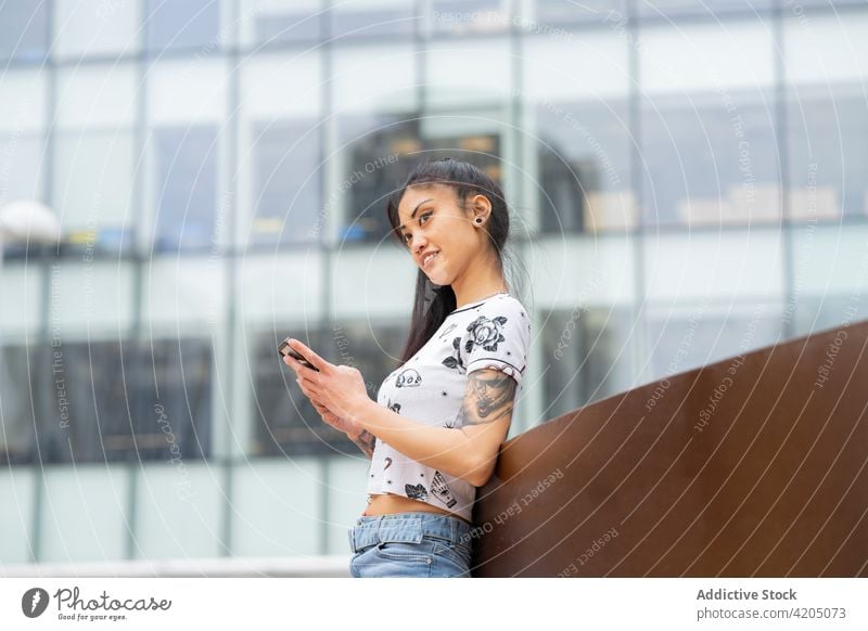 Asian woman using smartphone on street city rest lean urban style modern ethnic asian young mobile browsing tattoo online internet connection gadget device