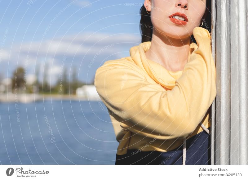 Anonymous trendy teen standing against rippled river adolescent individuality style confident casual millennial blue sky portrait atmosphere fence stylish cool