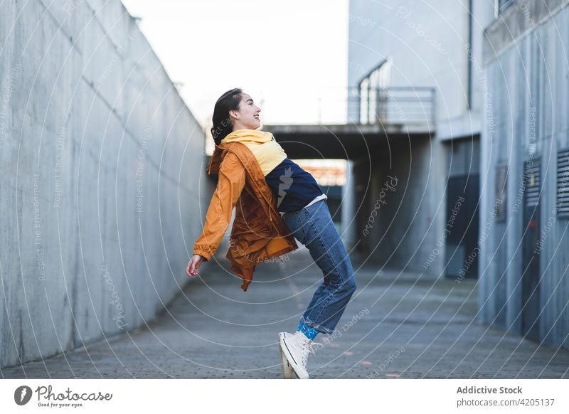 Smiling trendy teen on tiptoes in town having fun lean back smile casual enjoy road city style cool content glad happy cheerful roadway asphalt building