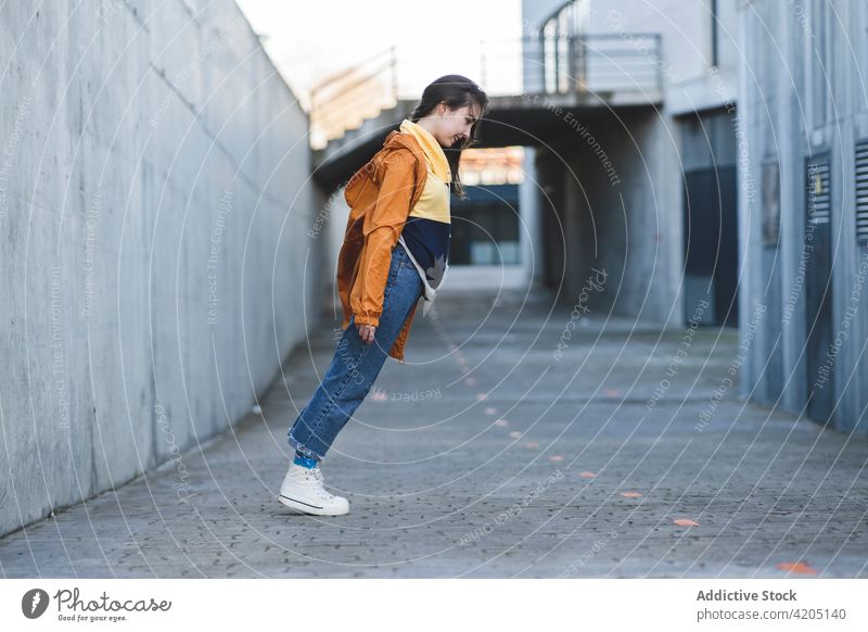 Smiling trendy teen having fun in town tiptoe lean back smile casual enjoy road city style cool content glad happy cheerful roadway asphalt lean forward