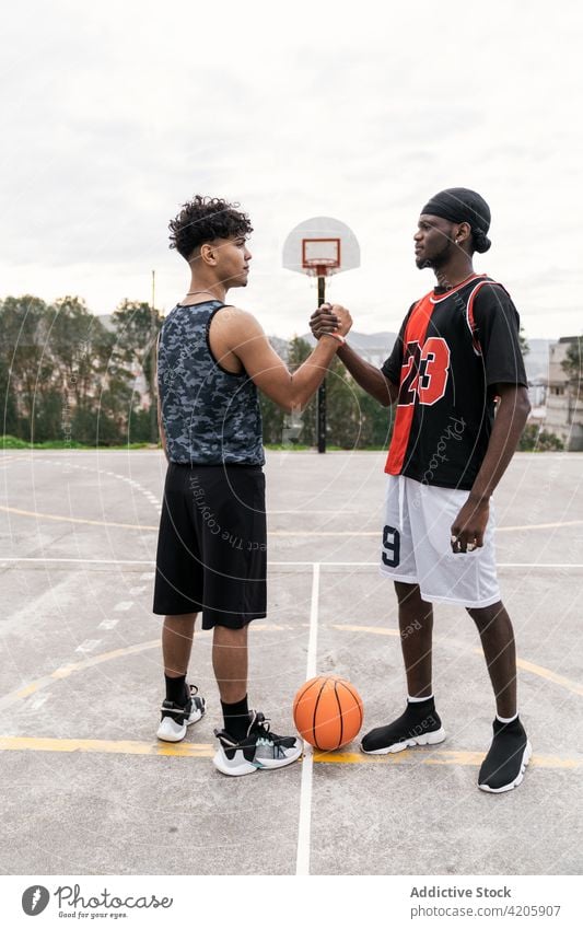 Black male basketball players shaking hands on court handshake men greeting gesture streetball playground together ethnic black african american game athlete