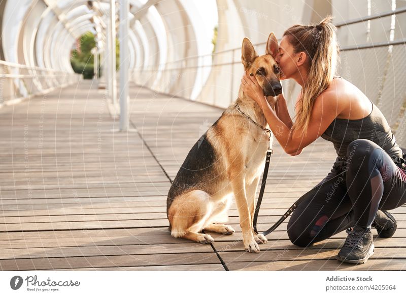 Young female owner kissing purebred dog during training woman german shepherd runner petting stroke workout canine together leash sport fitness companion friend